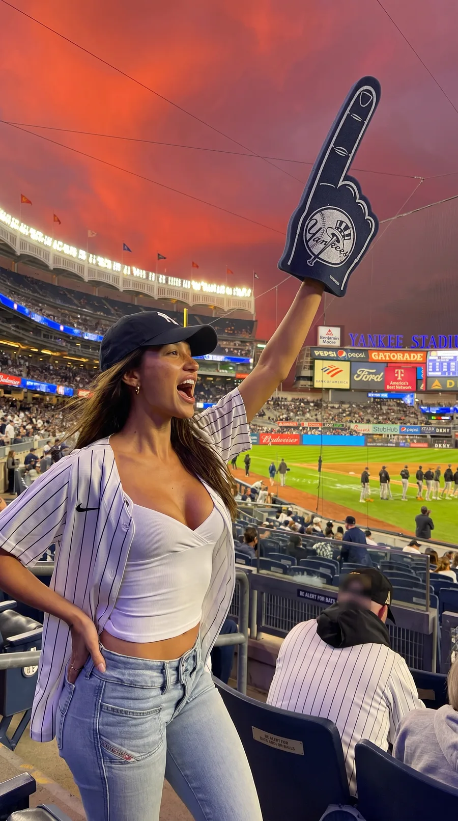 Chiara cheering at a baseball game with a foam finger