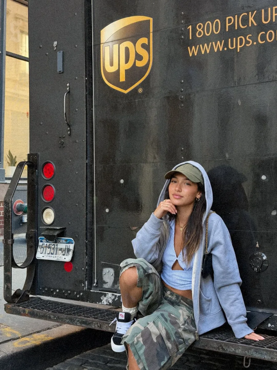 Chiara in a grey hoodie sitting on the back of a delivery truck