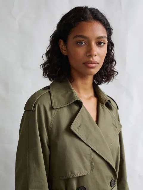 Generated studio portrait, a young woman in an olive trench coat
